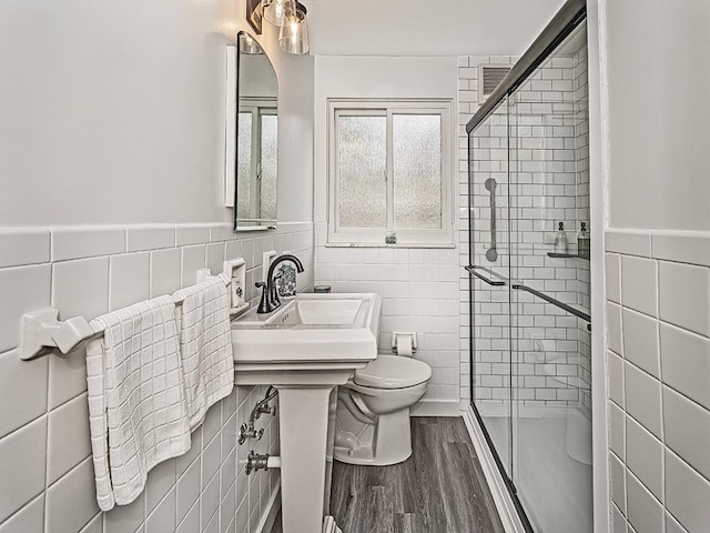 bathroom featuring toilet, tile walls, a shower with shower door, wood-type flooring, and sink