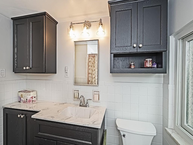 bathroom with tile walls, vanity, and toilet