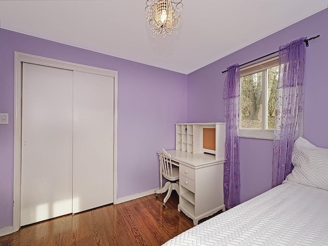 bedroom with dark wood-type flooring, an inviting chandelier, and a closet