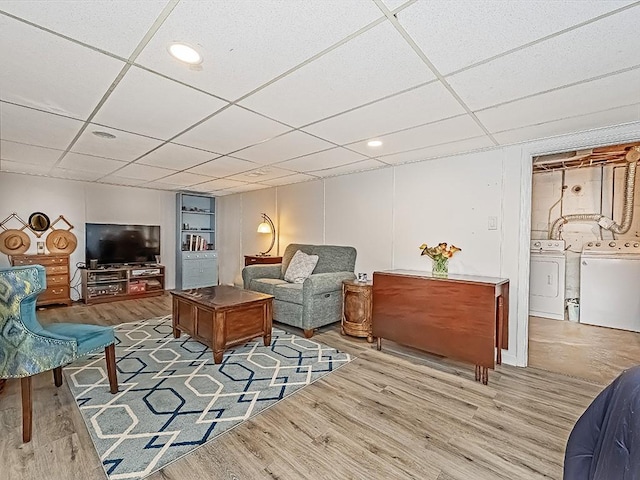 living room with a paneled ceiling, washing machine and dryer, and hardwood / wood-style flooring