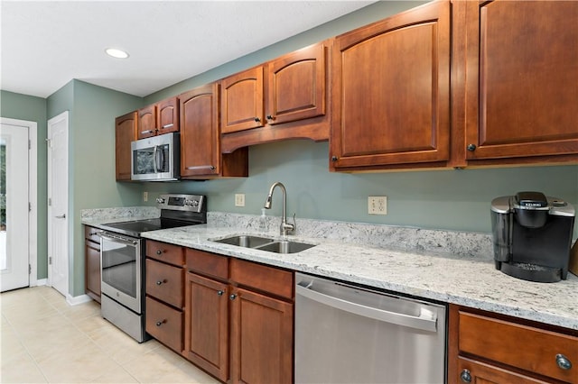 kitchen with light stone countertops, appliances with stainless steel finishes, light tile patterned floors, and sink