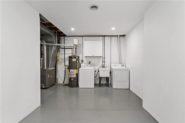 washroom with sink, cabinets, washing machine and dryer, and gas water heater