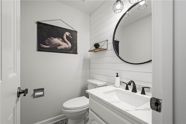 bathroom with toilet, wood walls, and vanity