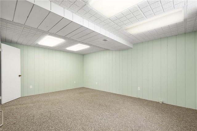 empty room featuring wooden walls and carpet flooring