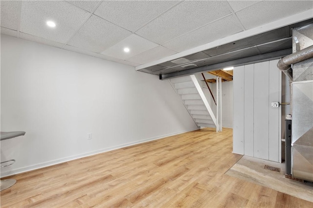 basement featuring light wood-type flooring and a drop ceiling