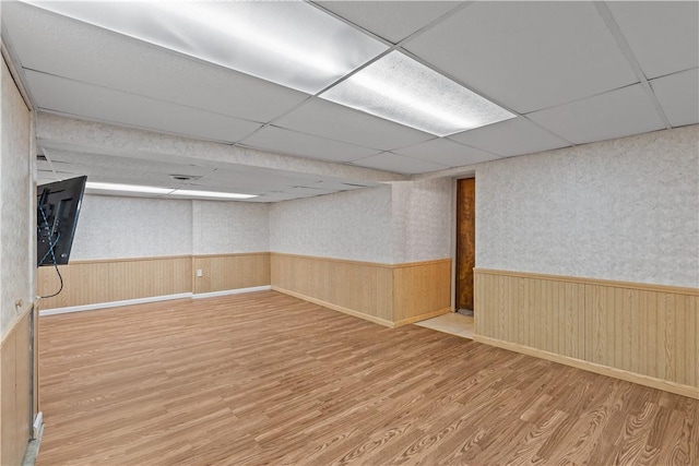 basement featuring a drop ceiling and light hardwood / wood-style floors