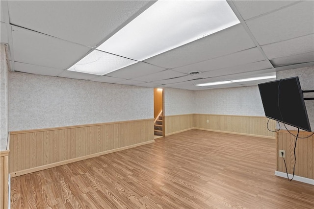 basement with wood-type flooring and a paneled ceiling