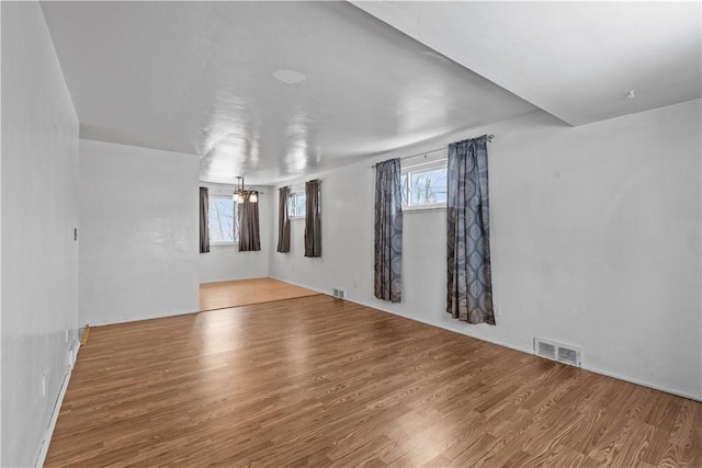 empty room featuring hardwood / wood-style flooring and a chandelier