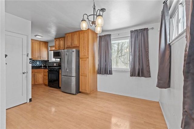 kitchen featuring a chandelier, decorative light fixtures, decorative backsplash, light wood-type flooring, and appliances with stainless steel finishes