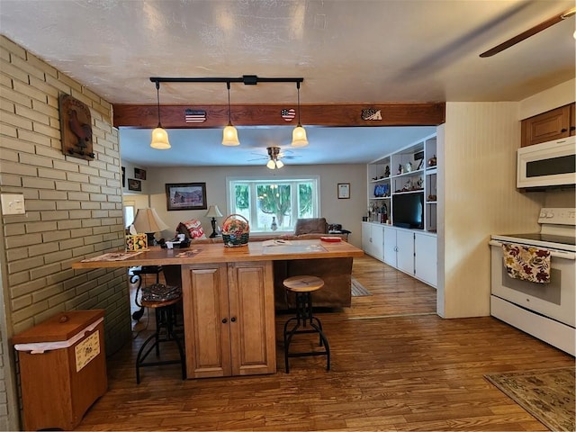 kitchen featuring white appliances, a kitchen breakfast bar, brick wall, and hanging light fixtures