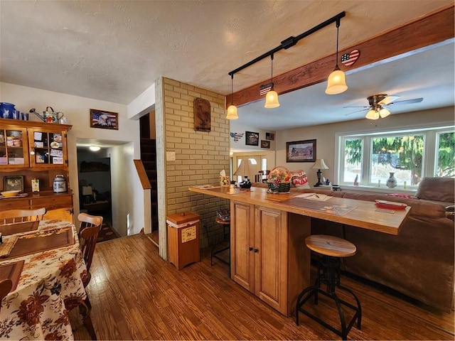 kitchen with dark hardwood / wood-style flooring, kitchen peninsula, pendant lighting, and a breakfast bar area