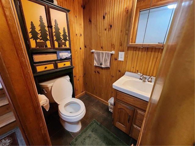 bathroom with toilet, wood walls, tile patterned floors, and vanity