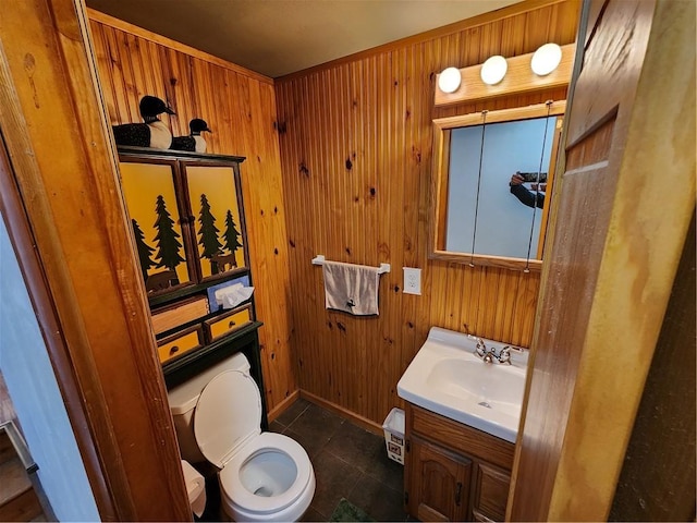 bathroom featuring vanity, tile patterned flooring, toilet, and wood walls