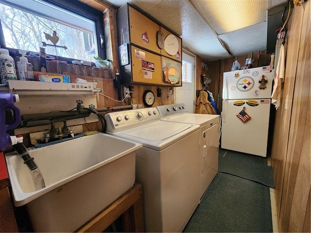 clothes washing area featuring plenty of natural light, washer hookup, wooden walls, and sink