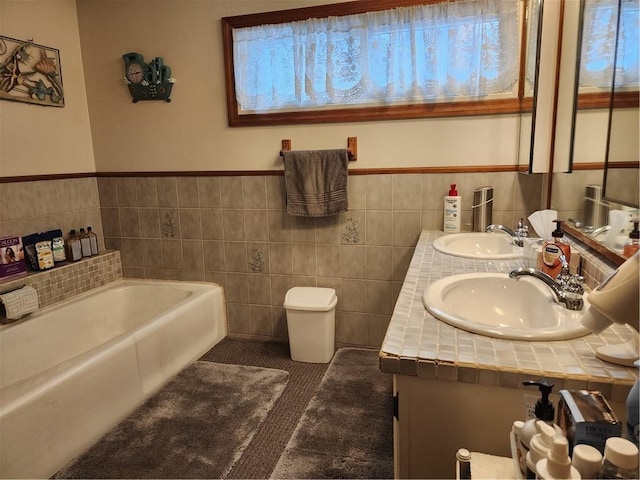 bathroom featuring tile walls, vanity, tile patterned floors, and a bathing tub