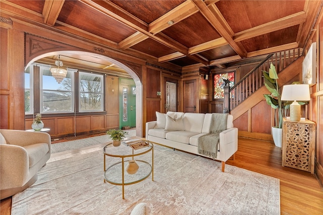 living room with wood walls, beamed ceiling, crown molding, wooden ceiling, and coffered ceiling