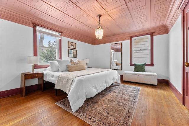 bedroom with a notable chandelier, light hardwood / wood-style floors, and crown molding