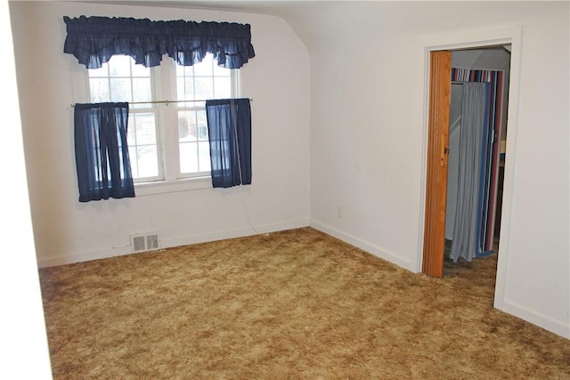 carpeted empty room with vaulted ceiling