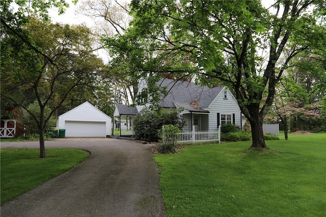 view of front of property with a detached garage, an outbuilding, and a front lawn