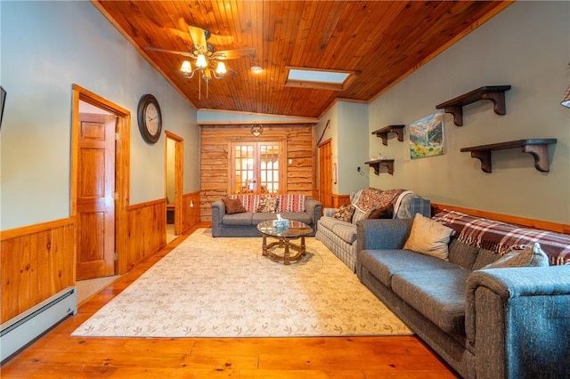 living room with baseboard heating, ceiling fan, lofted ceiling with skylight, and wood ceiling