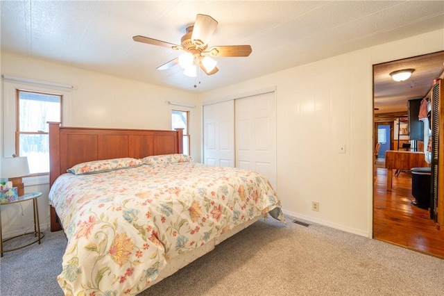 carpeted bedroom with ceiling fan, a closet, and multiple windows