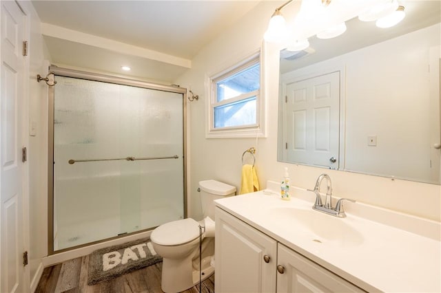 bathroom featuring toilet, vanity, a shower with shower door, and hardwood / wood-style floors