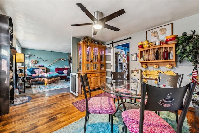 dining space featuring ceiling fan, hardwood / wood-style floors, and a barn door