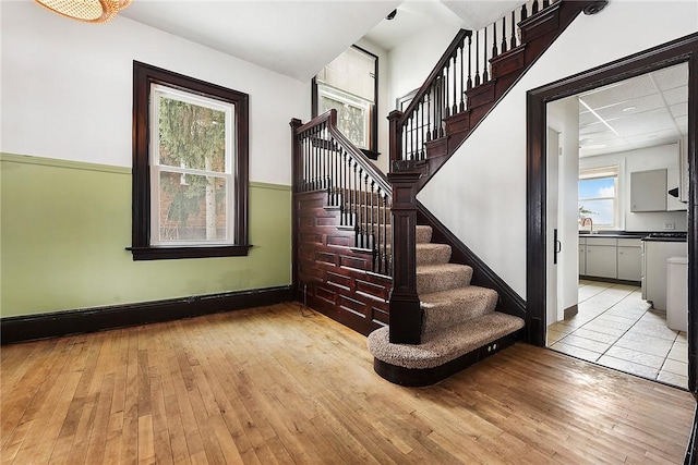 stairway featuring sink, a paneled ceiling, and hardwood / wood-style floors