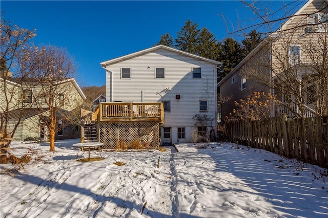 snow covered back of property with a wooden deck