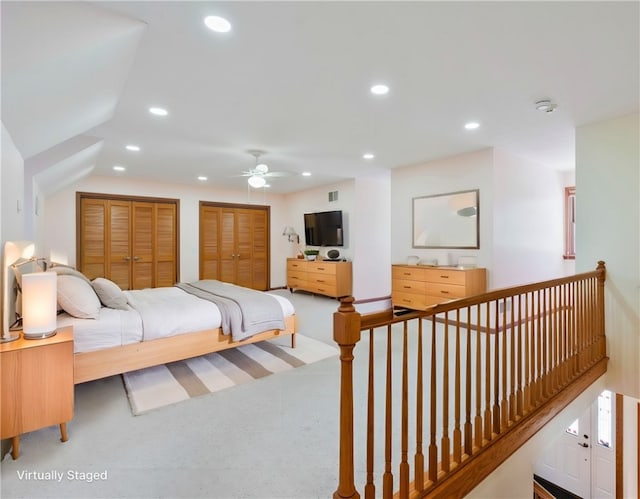 bedroom with ceiling fan, two closets, carpet, and vaulted ceiling