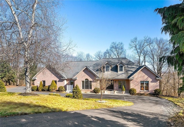 view of front of home featuring a front yard, brick siding, and driveway