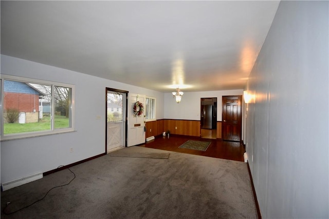 carpeted empty room with an inviting chandelier and wood walls