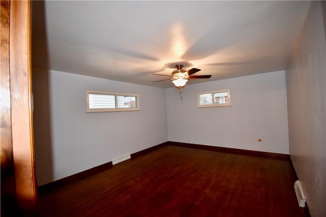 unfurnished room with ceiling fan, dark hardwood / wood-style floors, and a baseboard heating unit