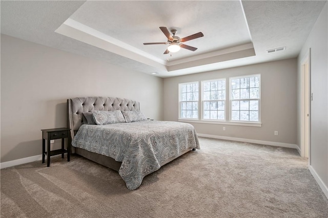 carpeted bedroom featuring ceiling fan and a tray ceiling