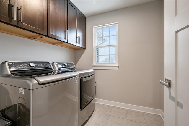 washroom with washer and clothes dryer, light tile patterned flooring, and cabinets