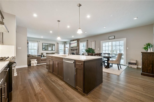 kitchen featuring sink, decorative light fixtures, an island with sink, dark hardwood / wood-style flooring, and appliances with stainless steel finishes