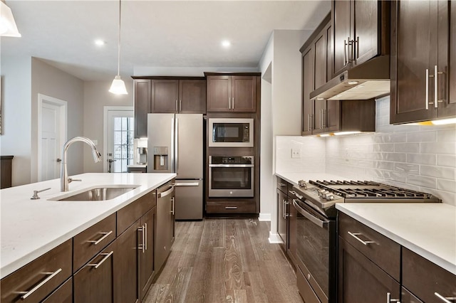 kitchen with appliances with stainless steel finishes, pendant lighting, sink, dark brown cabinets, and tasteful backsplash