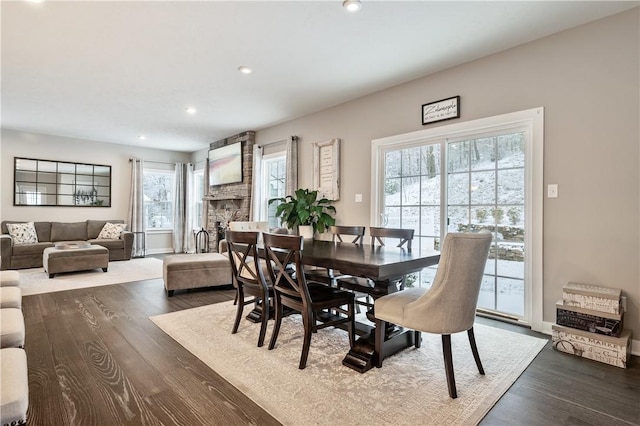 dining room with a stone fireplace and hardwood / wood-style flooring