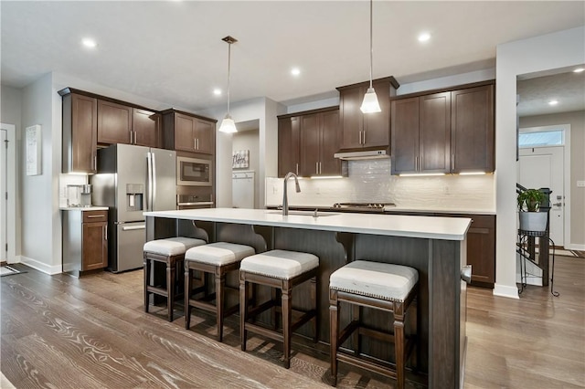 kitchen featuring sink, stainless steel appliances, a center island with sink, and pendant lighting