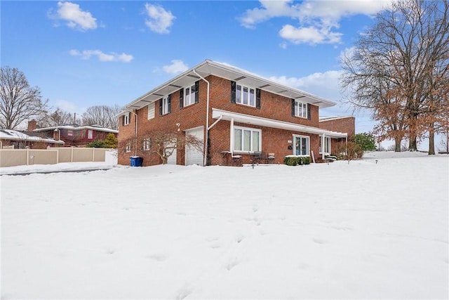 snow covered rear of property with a garage