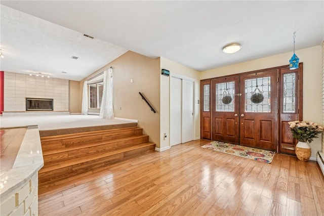 entrance foyer with a fireplace, a baseboard heating unit, light hardwood / wood-style flooring, and a wealth of natural light