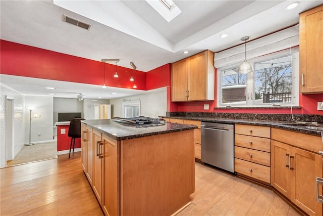 kitchen with light hardwood / wood-style floors, stainless steel appliances, pendant lighting, a kitchen island, and vaulted ceiling with skylight