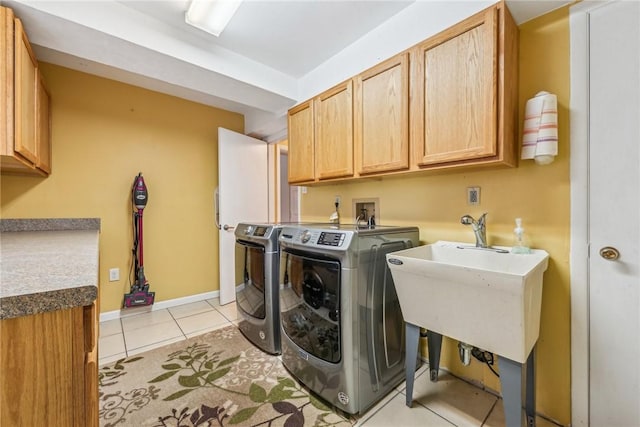 clothes washing area featuring washer and dryer, cabinets, and light tile patterned flooring