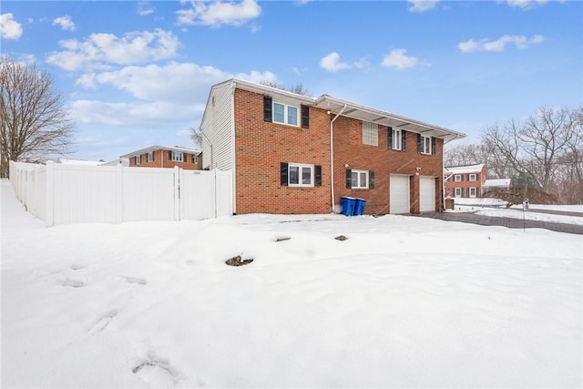 snow covered rear of property featuring a garage