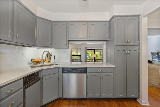 kitchen featuring stainless steel dishwasher, dark hardwood / wood-style flooring, sink, and gray cabinets