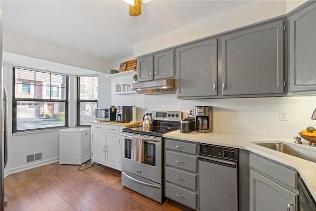 kitchen featuring stainless steel appliances, gray cabinets, and tasteful backsplash