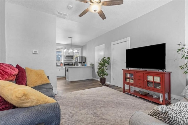 living room featuring ceiling fan with notable chandelier and hardwood / wood-style flooring