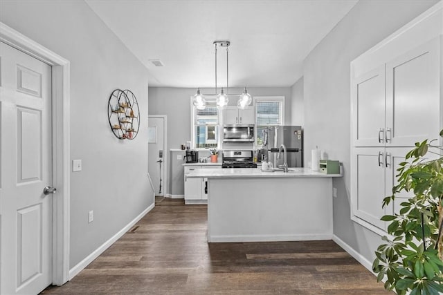 kitchen with kitchen peninsula, dark hardwood / wood-style floors, decorative light fixtures, stainless steel appliances, and white cabinets