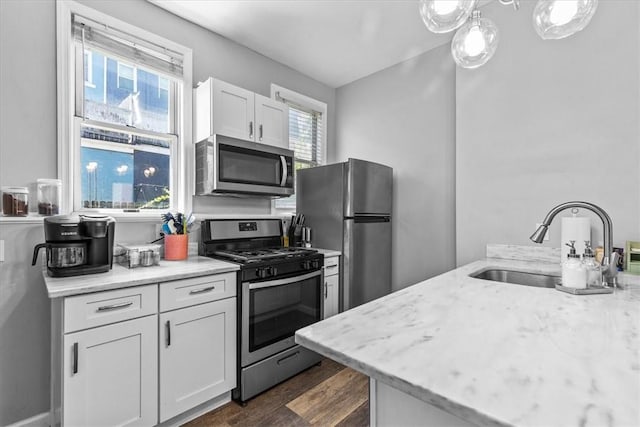 kitchen with appliances with stainless steel finishes, light stone countertops, dark wood-type flooring, white cabinets, and sink