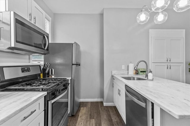 kitchen featuring appliances with stainless steel finishes, plenty of natural light, sink, white cabinetry, and decorative light fixtures